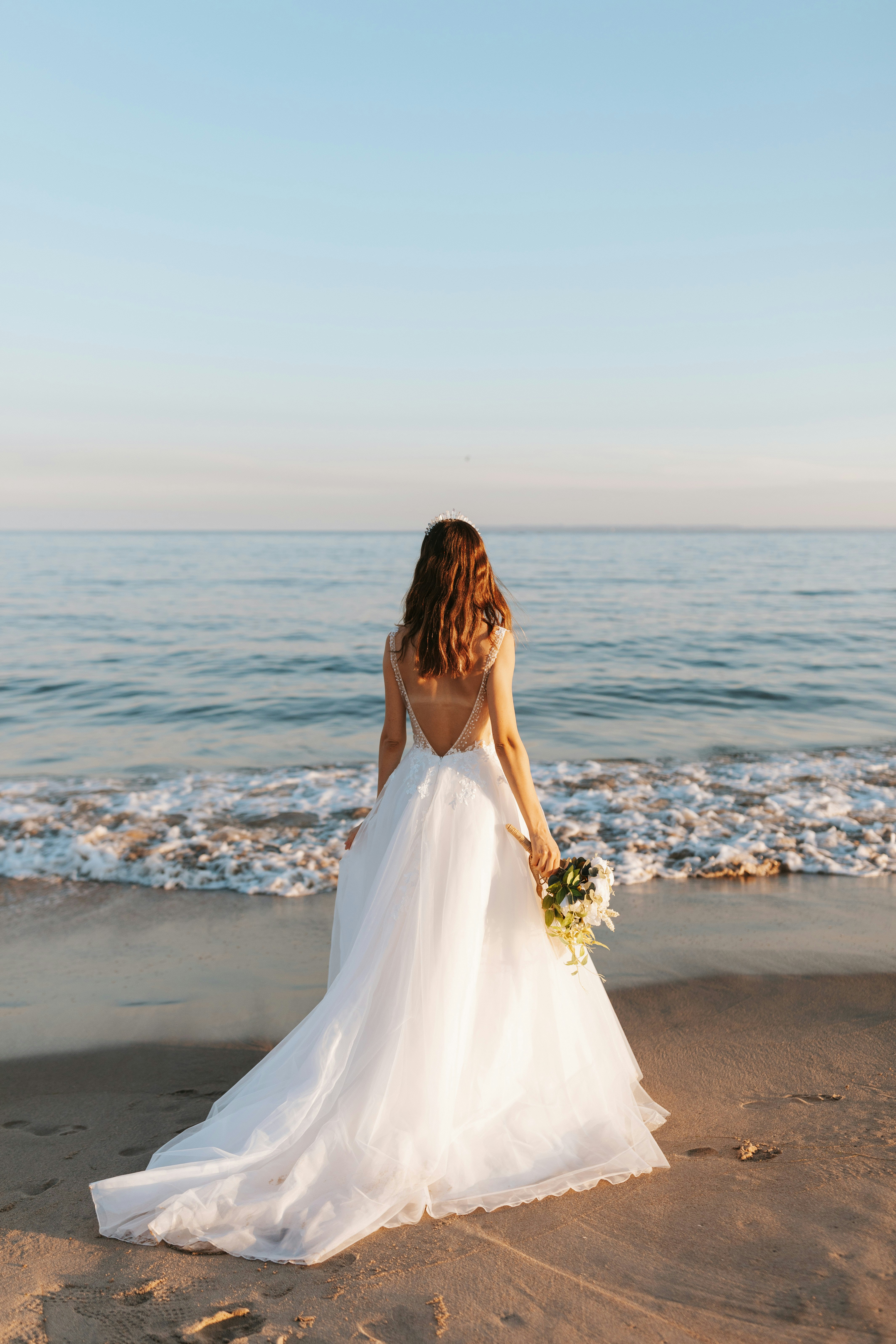 woman in wedding dress along the shore of a beach